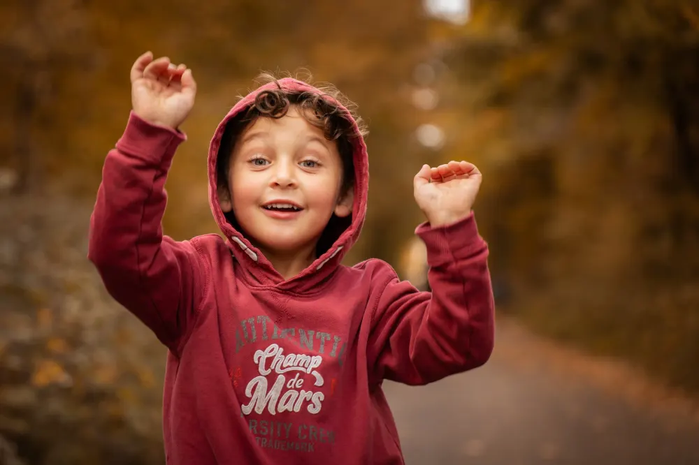 Séance photo de Noël à Salins (77) : un enfant en sweat rouge dans un décor d'automne