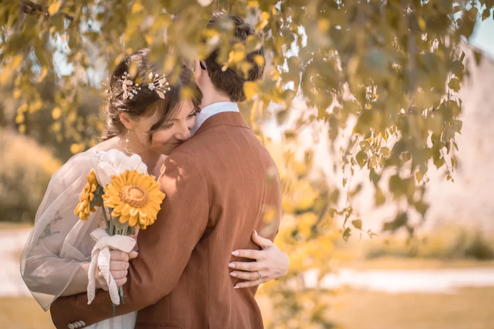 Mariage d'automne près de Salins : les mariés enlacés, bouquet de tournesols à la main