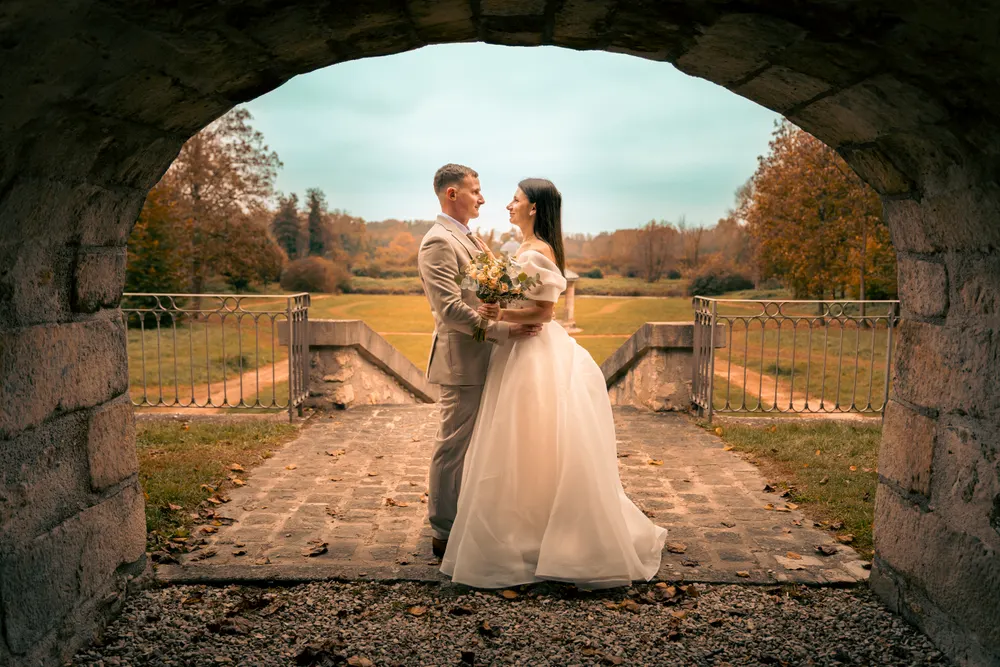 Photographe mariage à Salins (77) : mariés sous une arche en pierre, parc en automne