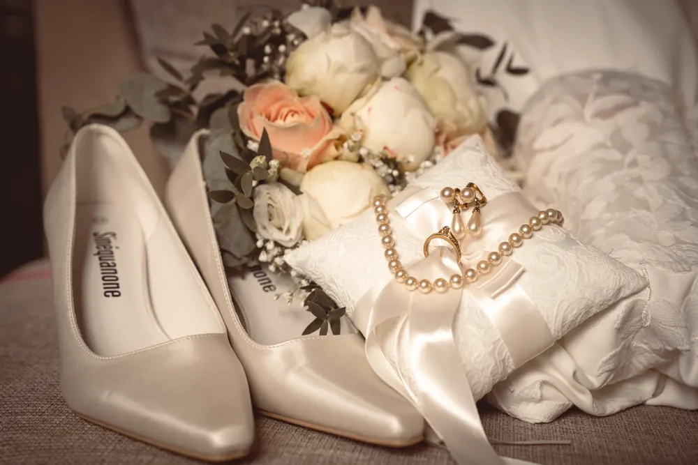 Reportage mariage à Salins (77) : détails du mariage, escarpins, bouquet de roses et alliances sur un coussin