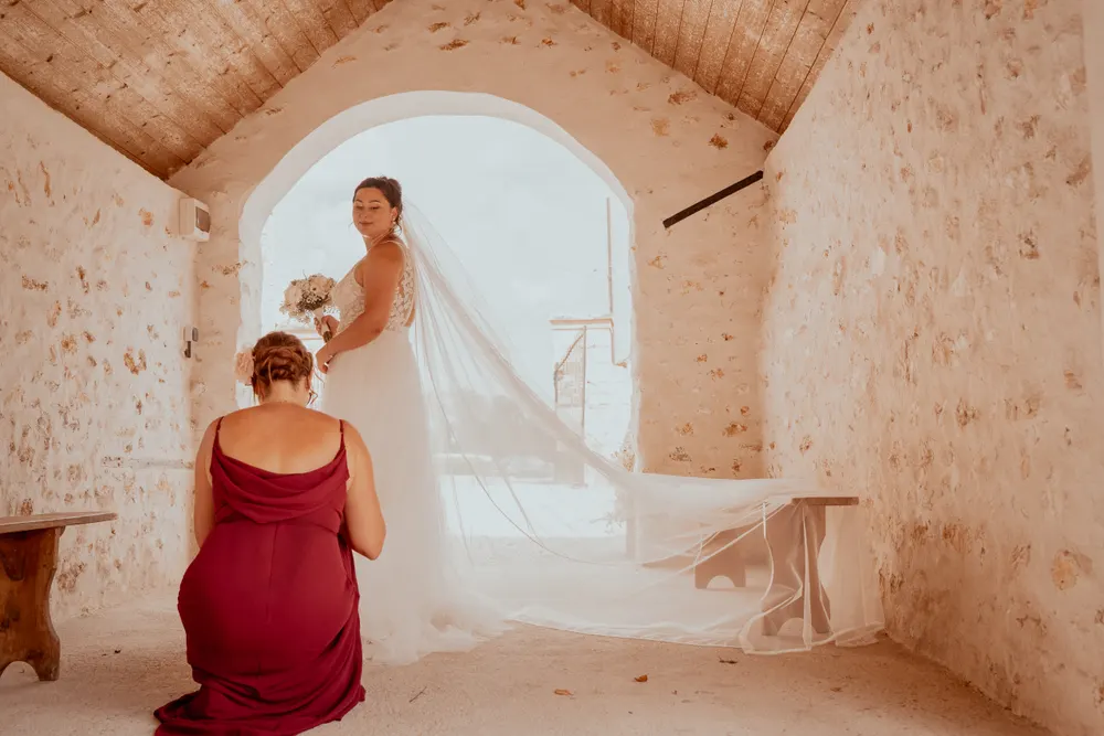 Reportage photo mariage en Seine-et-Marne : préparatifs de la mariée, son voile déployé dans une pièce aux murs de pierre